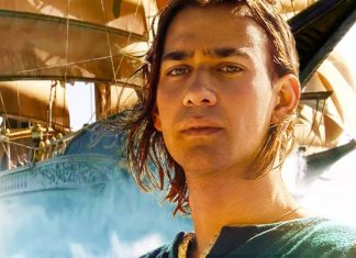 Homem de cabelo longo com navio ao fundo.