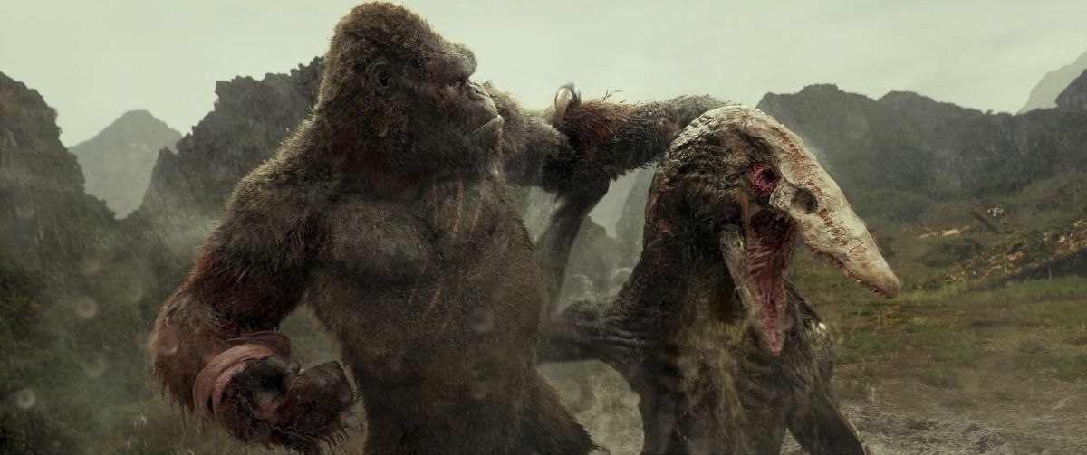 Gorila gigante lutando contra dinossauro em ambiente montanhoso.