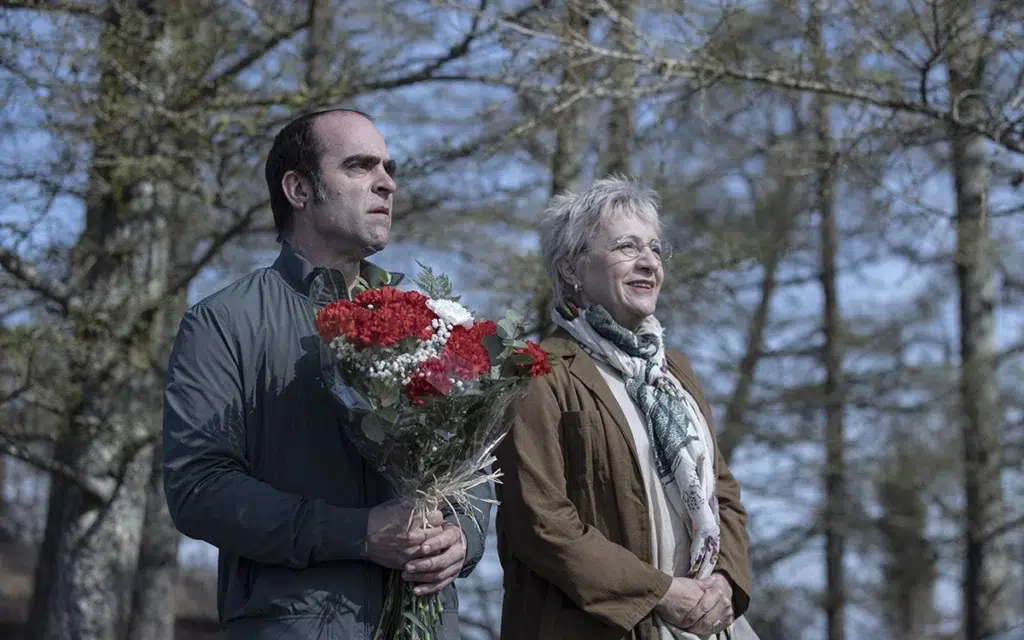 Homem e mulher com buquê de flores ao ar livre.