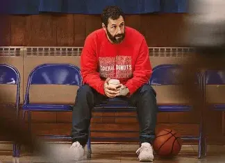 10 Filmes que todo amante dos ESPORTES deve conferir Homem sentado em uma arquibancada com bola de basquete.