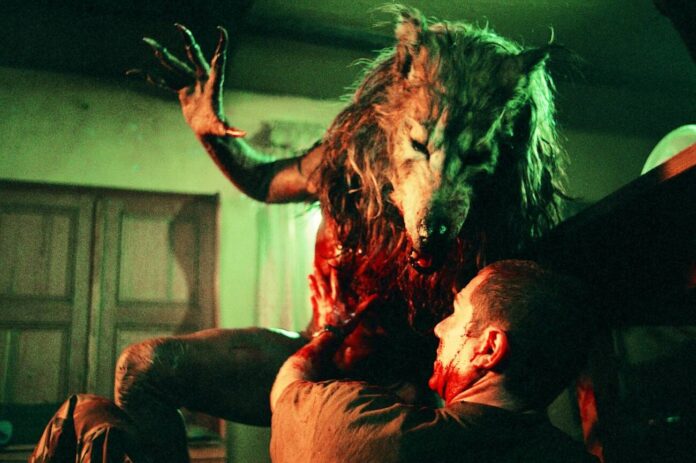 Homem sendo atacado por criatura lobo feroz.