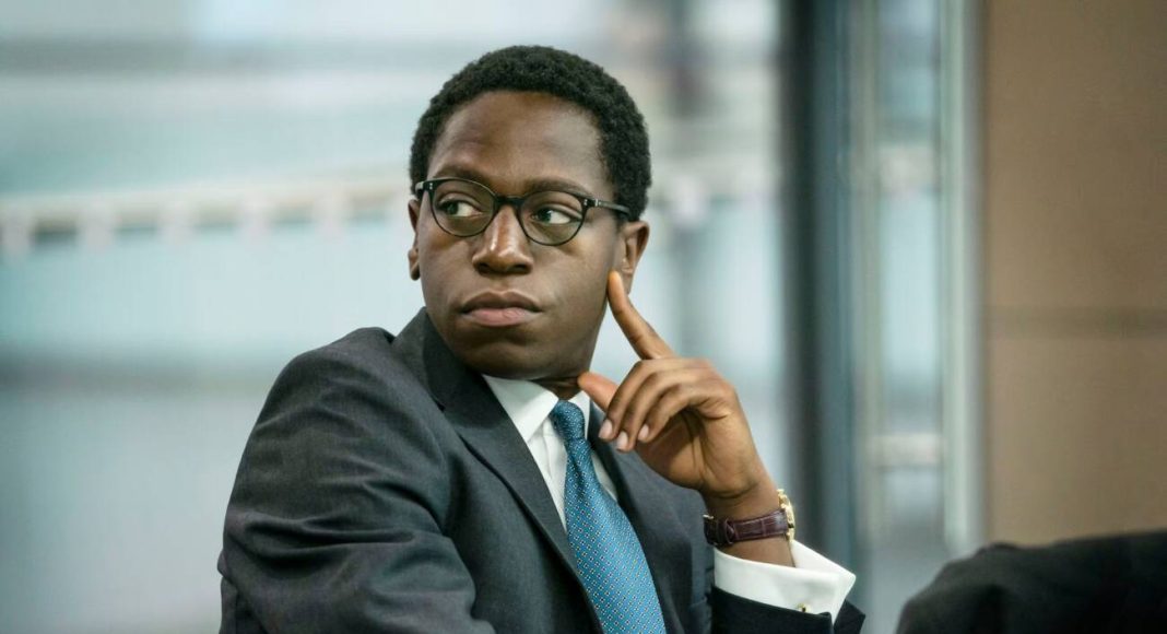 Homem de terno concentrado em reunião empresarial.