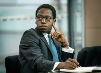 Homem de terno concentrado em reunião empresarial.