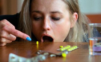 Mulher prestes a tomar comprimido amarelo.