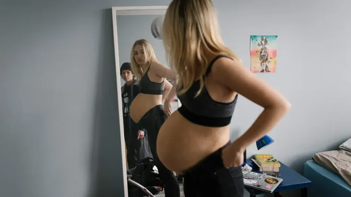 Mulher grávida se olhando no espelho.