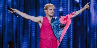 Cantor no palco com microfone e bandeira.