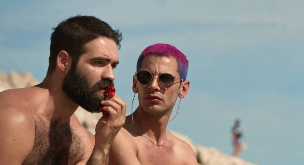 Dois homens conversando na praia em dia ensolarado.