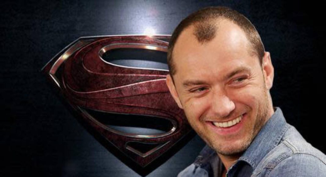 Homem sorridente com símbolo de Superman ao fundo.
