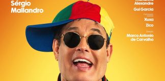 Homem com boné colorido e óculos escuros sorrindo.