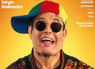 Homem com boné colorido e óculos escuros sorrindo.