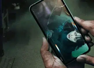 Pessoa assistindo vídeo em celular com tela quebrada.