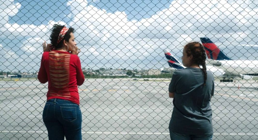 o estranho (1) Duas pessoas observando aviões através de uma cerca.