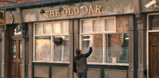 Pessoa retirando letreiro de madeira de uma fachada de loja.