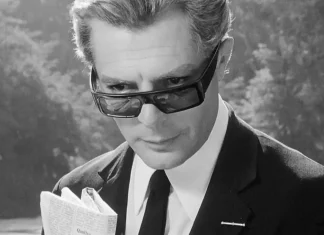 Homem de óculos escuros lendo jornal.