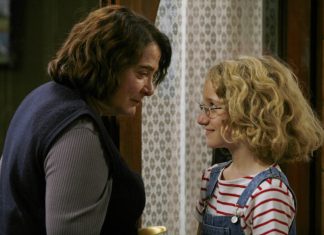 Mulher conversando com criança loira usando óculos.