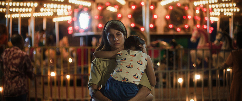 Mãe e filho em parque de diversões iluminado.