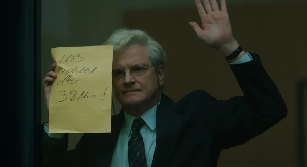 colin firth Homem segurando cartaz informativo em ambiente fechado.
