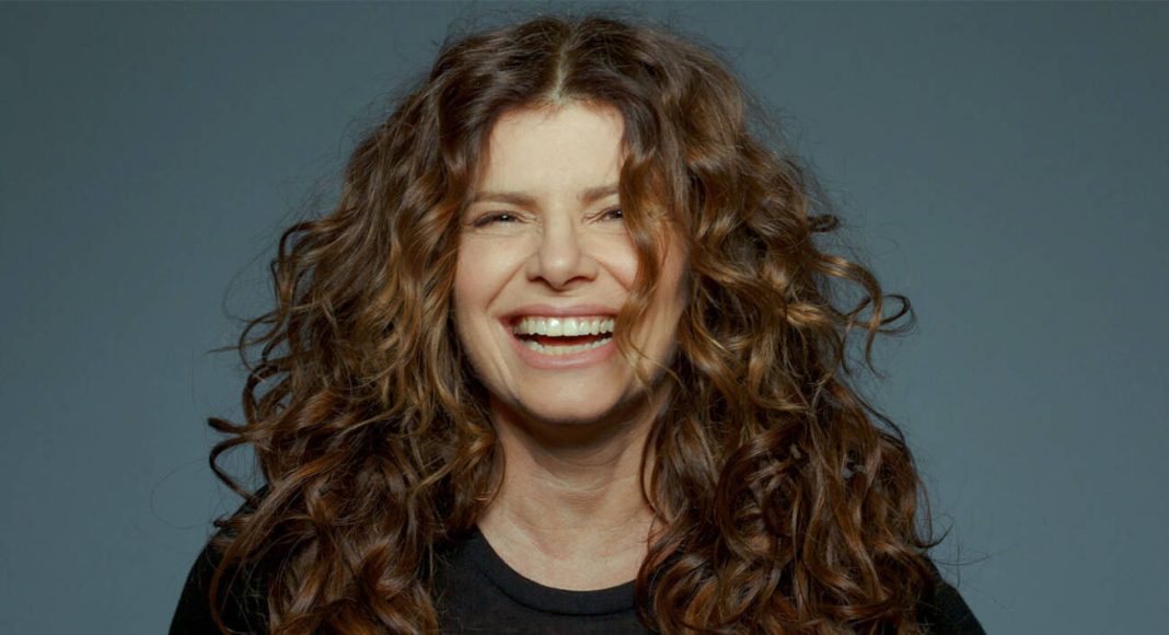 Mulher sorridente com cabelo cacheado castanho