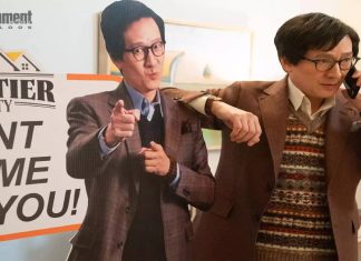 Homem falando ao telefone com cartaz de imobiliária.