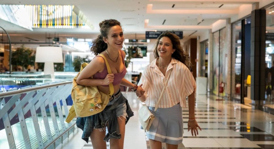 adoracao netflix Duas mulheres sorrindo em shopping center.