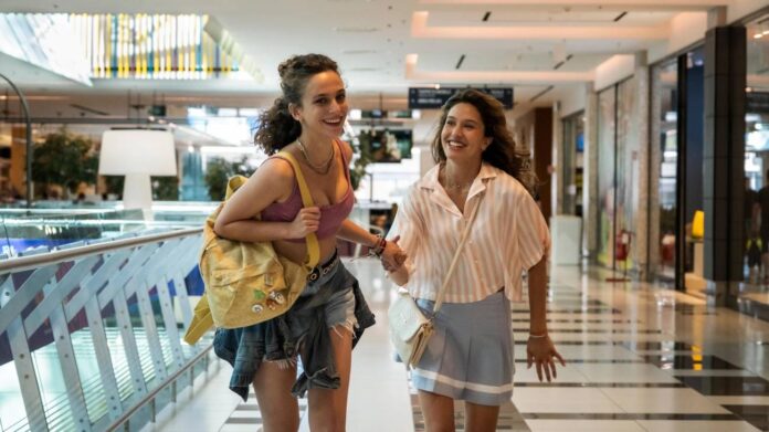 Duas mulheres sorrindo em shopping center.