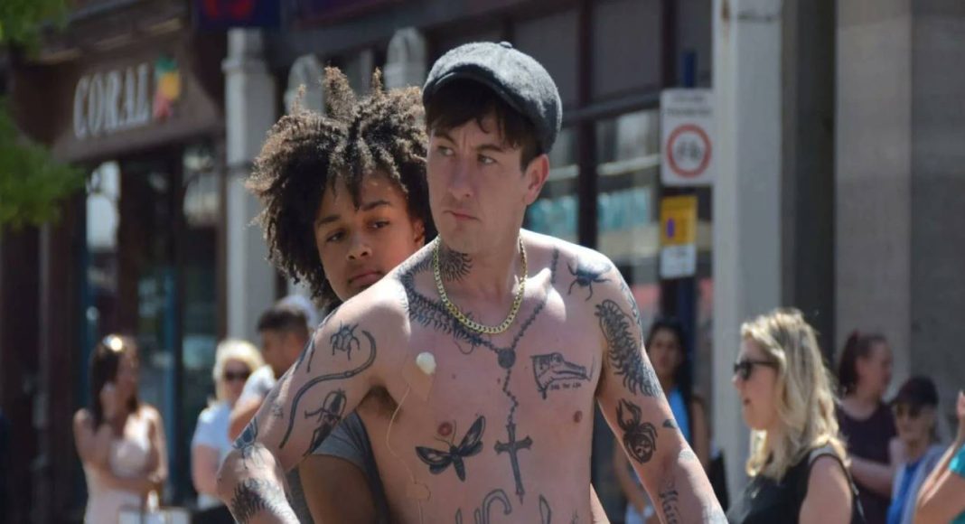 bird Homem tatuado na rua com pessoas ao fundo.