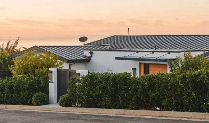 Casa moderna com telhado met&aacute;lico ao entardecer.