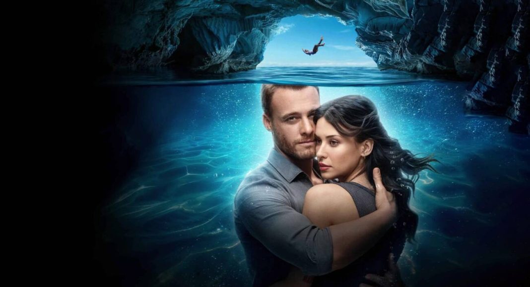 Casal abraçado em frente ao mar e caverna