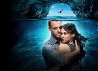 Casal abraçado em frente ao mar e caverna