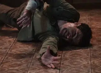 Homem ferido caído no chão, braço estendido
