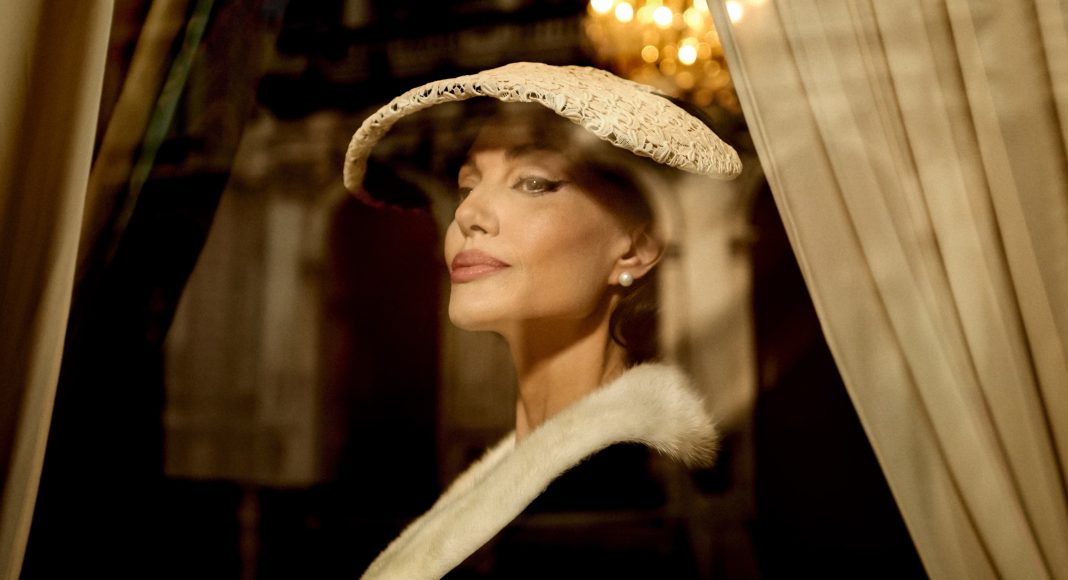 Mulher elegante usando chapéu e capa, ambiente sofisticado.