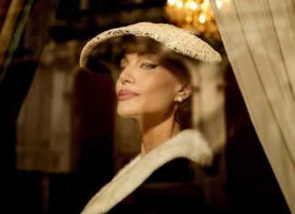 ‘Maria Callas’: Drama biográfico com Angelina Jolie estreia no streaming; Saiba onde assistir! Mulher elegante usando chapéu e capa, ambiente sofisticado.