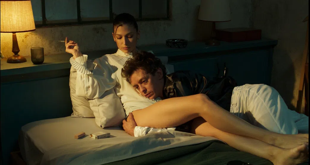 Casal em cena romântica em quarto escuro.