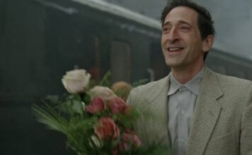 Homem sorrindo segurando buquê de flores na estação.