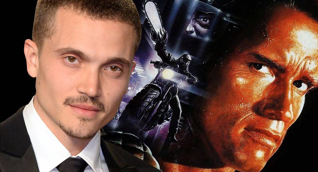 Homem de terno, pôster de filme ao fundo.