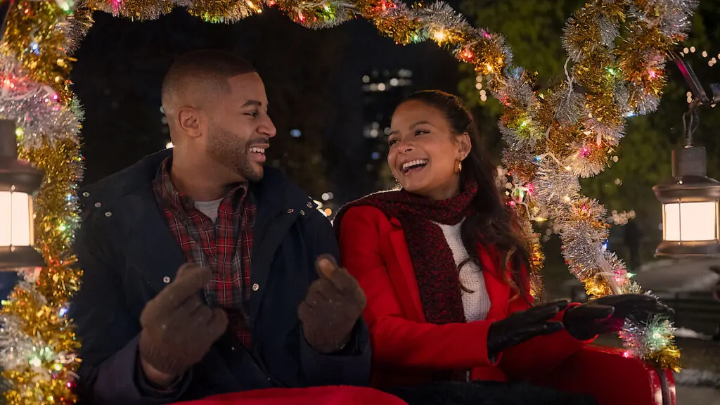 Casal sorrindo em carruagem natalina à noite.