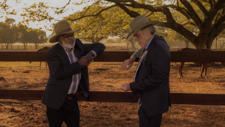 Dois homens conversam em fazenda com chap&eacute;us.