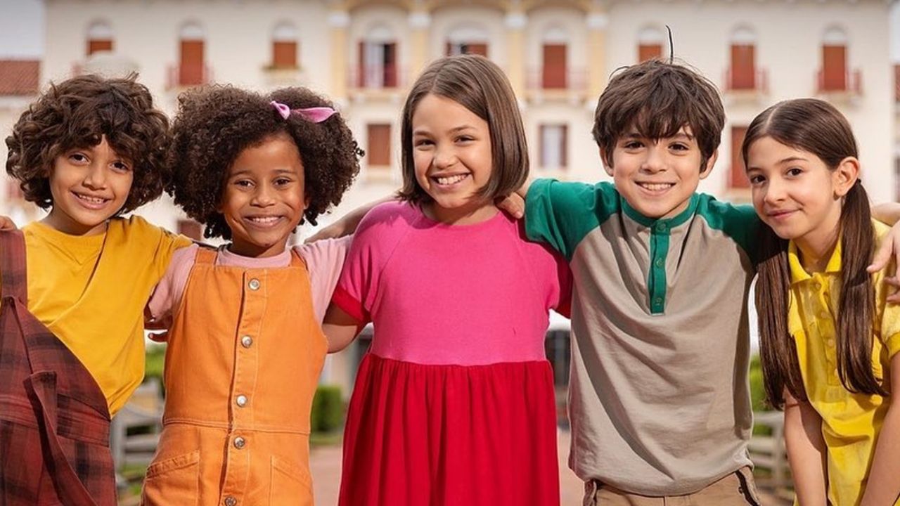 Crianças abraçadas, sorrindo em frente ao prédio.