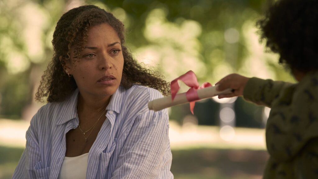 Mulher recebendo pergaminho de criança ao ar livre.