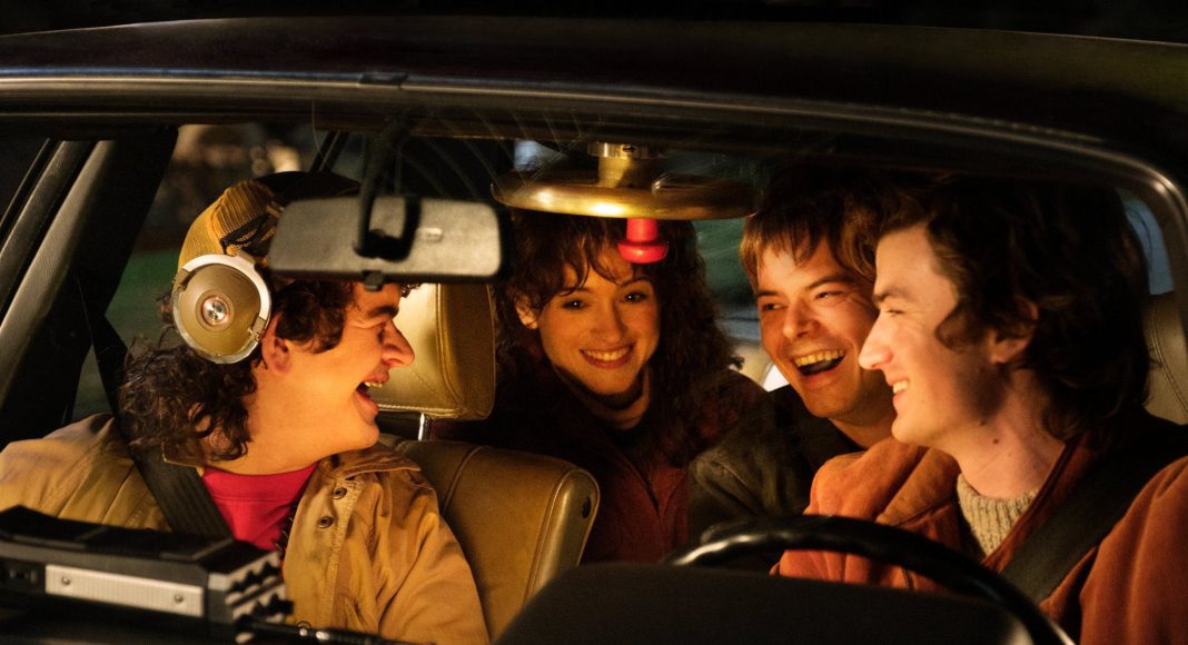 Grupo de amigos sorrindo dentro do carro à noite.