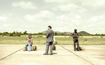 Três pessoas esperando em uma pista de pouso vazia