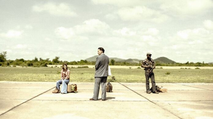 Três pessoas esperando em uma pista de pouso vazia