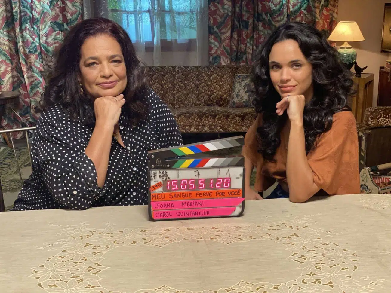 Duas atrizes em set de filmagem com claquete sobre mesa