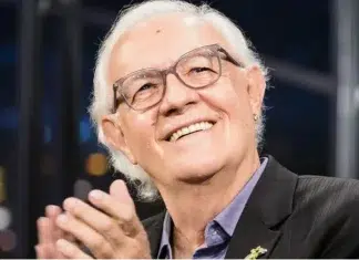 Homem sorridente com óculos em estúdio iluminado