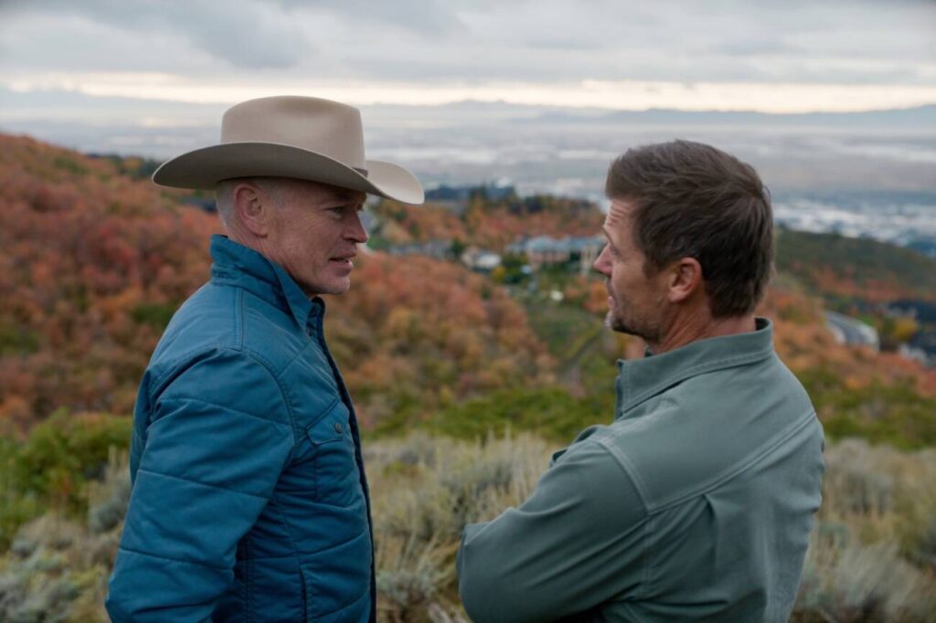 Dois homens conversando ao ar livre com vista para montanhas