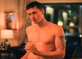 Homem sem camisa com copo na sala iluminada