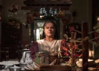 Mulher séria em cozinha rústica repleta de objetos