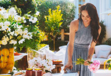 Mulher sorridente arranjando flores em mesa ao ar livre