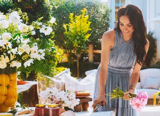 Mulher sorridente arranjando flores em mesa ao ar livre