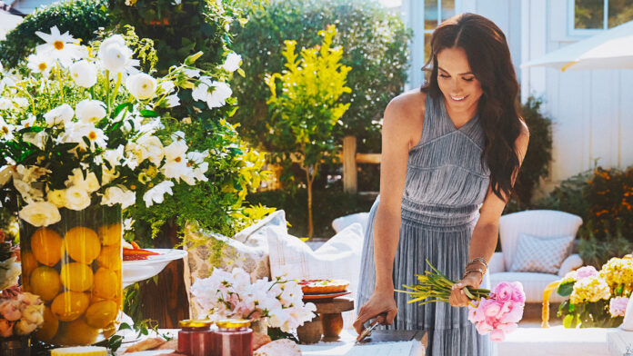 Mulher sorridente arranjando flores em mesa ao ar livre